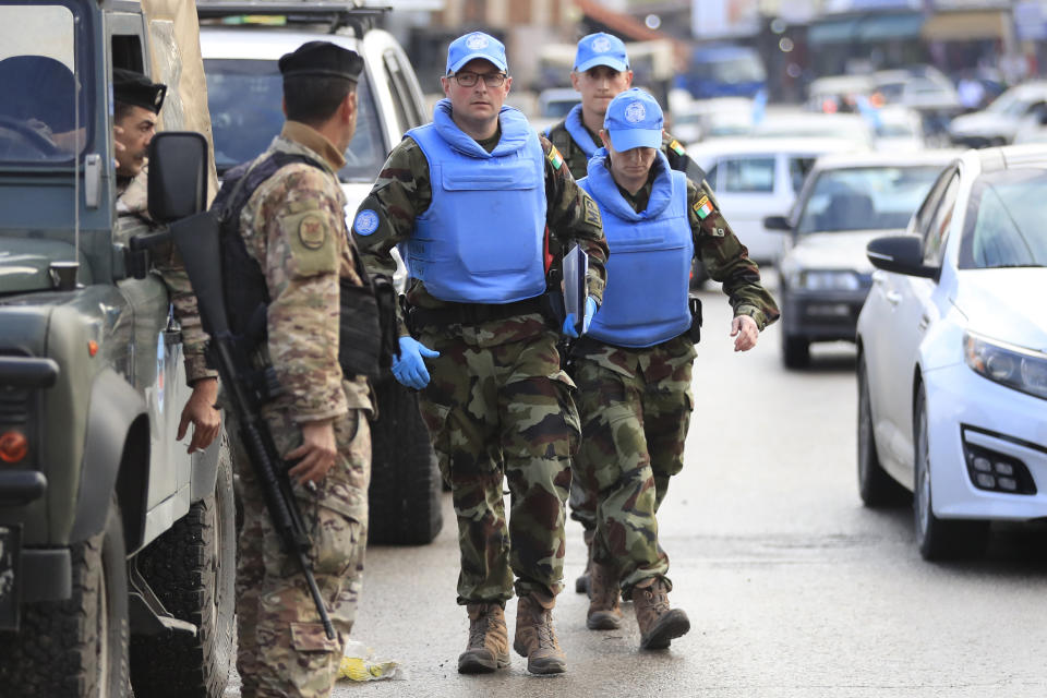 Irish UN peacekeepers pass a Lebanese soldier, left, as they arrive to investigate the scene where unidentified open gunfire came on a UN peacekeeper convoy in the Al-Aqbiya village, south Lebanon, Thursday, Dec. 15, 2022. (AP Photo/Mohammed Zaatari)