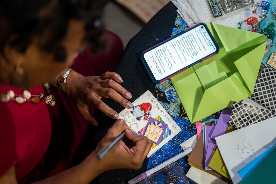 Alina Johnson, the owner of Johnson Consulting Services, works on creating handmade holiday greeting cards for friends and family at a workstation in the bedroom of her home in Detroit on Dec. 13, 2022, while incorporating a section of lyrics from their favorite Christmas song by the Temptations she looked up on her phone. Johnson sometimes carves out substantial time to make the cards where she incorporates calligraphy and origami envelopes and also sells her creations to Detroiters and other local people who care enough to give cards that make a personal, heartfelt statement during the holiday season.