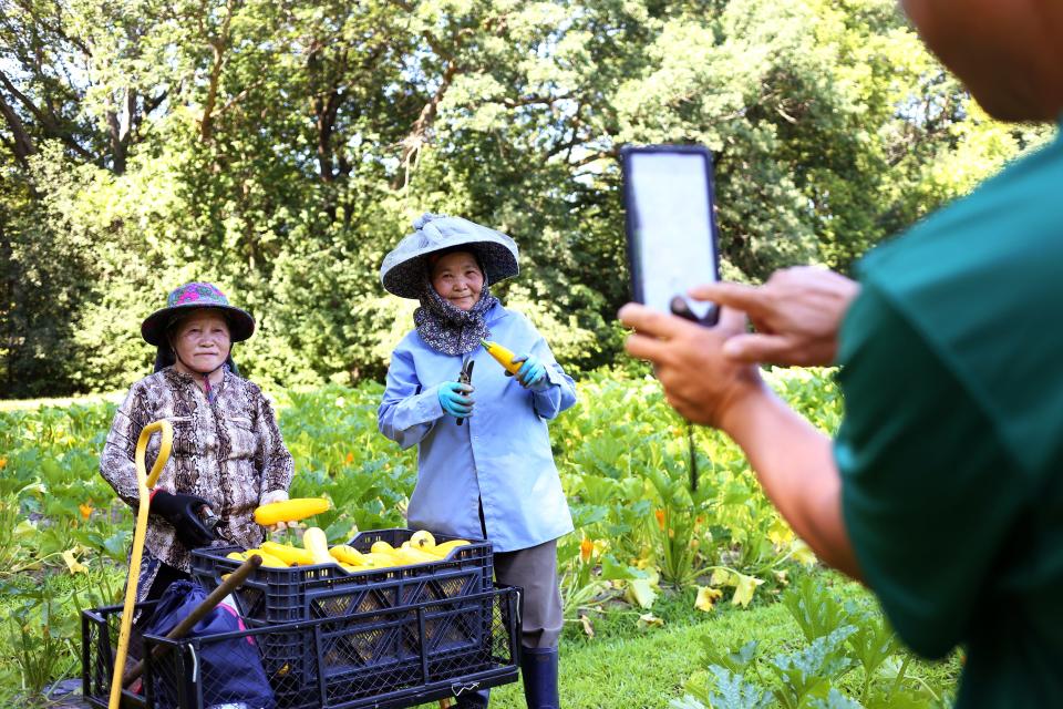 Chee Thao, left, and Mao Vue pose as Long Vue, the executive director of NEW Hmong Professionals, takes a photo of them on July 18 at Riverview Gardens in Appleton.