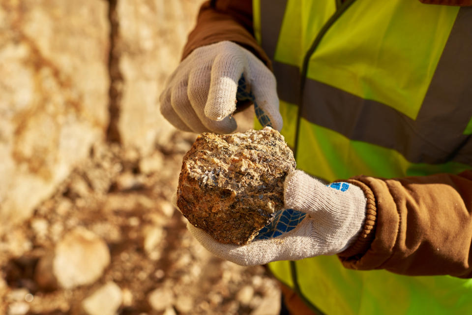 A gold miner holding up a chunk of ore.