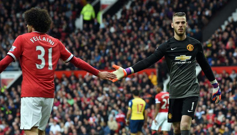 Manchester United goalkeeper David de Gea touches the hand of midfielder Marouane Fellaini during the Premier League match against Arsenal at Old Trafford on May 17, 2015