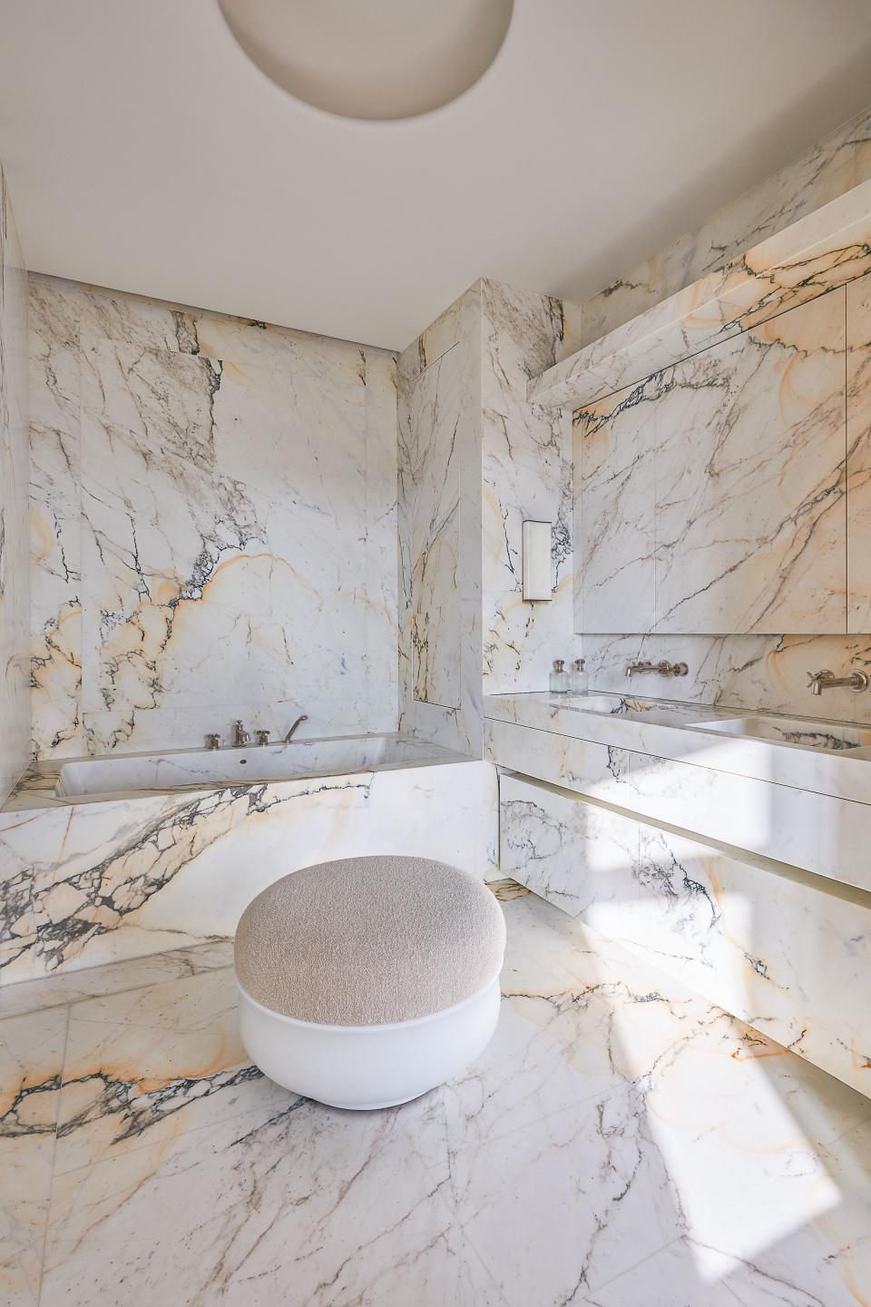 Paonazzo marble clads the bath. Eric Schmitt bronze-and-fabric pouf; Waterworks sink and tub fittings.