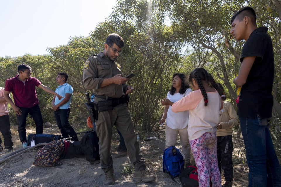 Border Patrol agents talk with migrants seeking asylum as they prepare them for transportation to be processed, Wednesday, June 5, 2024, near Dulzura, Calif. President Joe Biden on Tuesday unveiled plans to enact immediate significant restrictions on migrants seeking asylum at the U.S.-Mexico border as the White House tries to neutralize immigration as a political liability ahead of the November elections. (AP Photo/Gregory Bull)