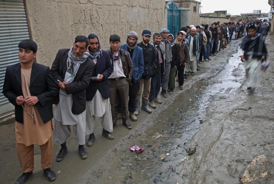 Afghan men line up for the registration process before they cast their votes at a polling station in Kabul, Afghanistan, Saturday, April 5, 2014. Afghans flocked to polling stations nationwide on Saturday, defying a threat of violence by the Taliban to cast ballots in what promises to be the nation's first democratic transfer of power. The vote will decide who will replace President Hamid Karzai, who is barred constitutionally from seeking a third term. (AP Photo/Massoud Hossaini)