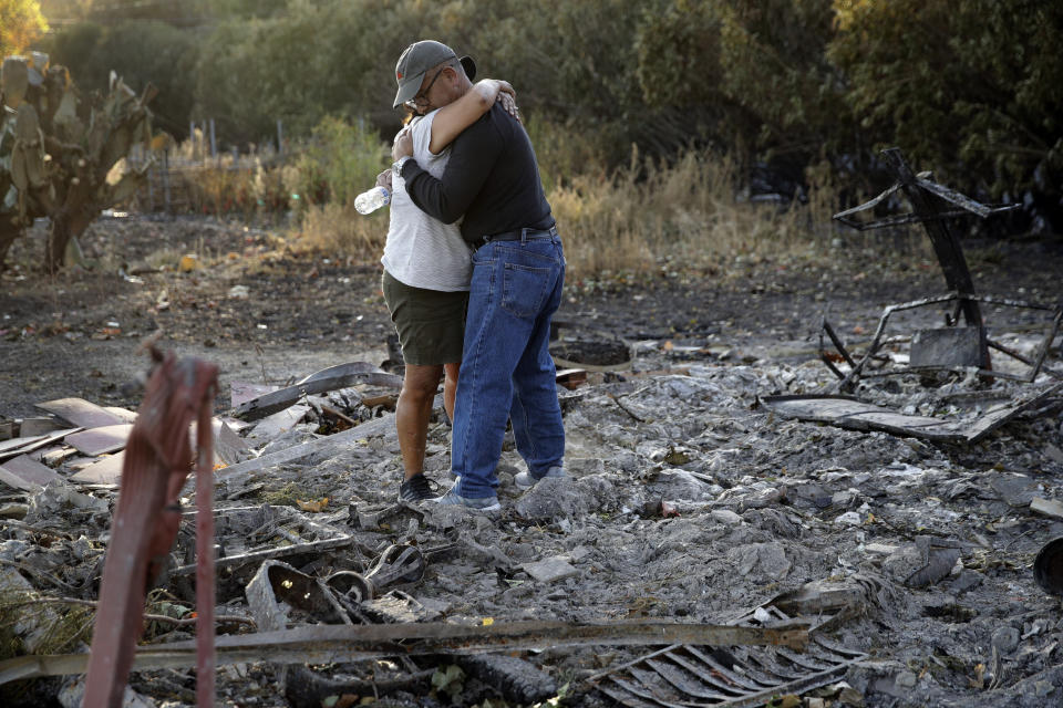 Justo and Bernadette Laos hug while looking through the charred remains of the home they rented that was destroyed by the Kincade Fire near Geyserville, Calif., Thursday, Oct. 31, 2019. The fire started last week near the town of Geyserville in Sonoma County north of San Francisco. (AP Photo/Charlie Riedel)