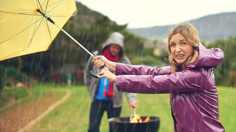 couple trying to grill in rain and wind