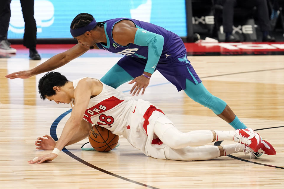 Toronto Raptors forward Yuta Watanabe, of Japan, (18) falls on the ball as he is guarded by Charlotte Hornets guard Devonte' Graham (4) during the first half of an NBA basketball game Thursday, Jan. 14, 2021, in Tampa, Fla. (AP Photo/Chris O'Meara)