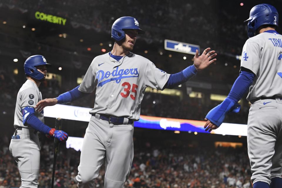 Los Angeles Dodgers' Cody Bellinger, center, celebrates with Chris Taylor after they both scored