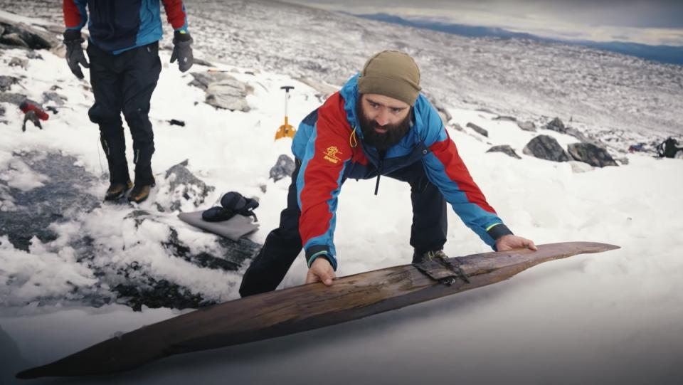 A researcher observes a 1,300-year-old ski on a snowy mountain in Norway..