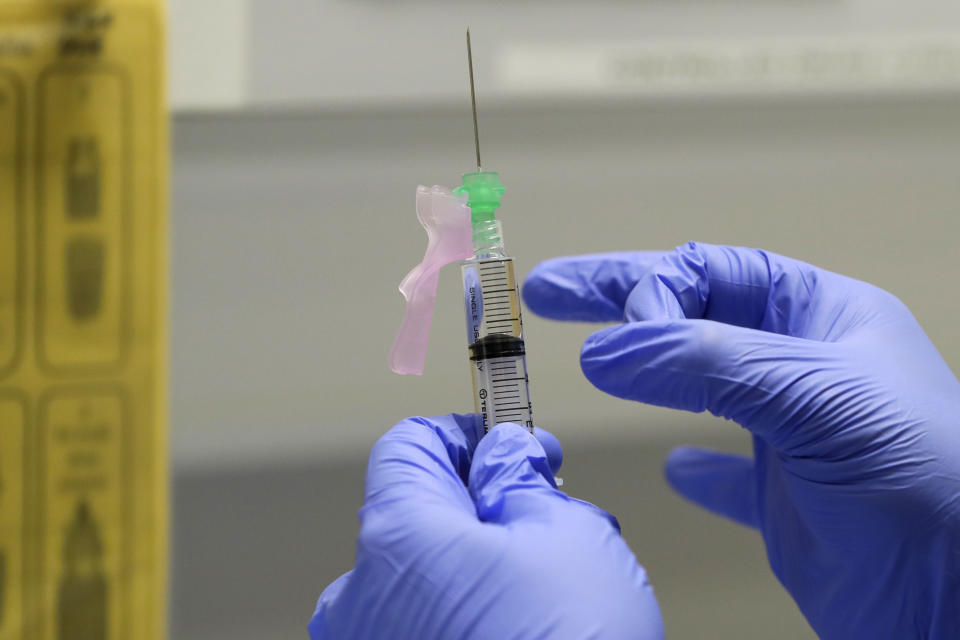 FILE - In this Wednesday, Aug. 5, 2020 file photo, senior Clinical Research Nurse Ajithkumar Sukumaran prepares the COVID 19 vaccine to administer to a volunteer, at a clinic in London. The British government on Thursday, Sept. 24, 2020 says it may take part in a study that tries to deliberately infect volunteers who have been given an experimental vaccine against the coronavirus in an effort to more quickly determine if the vaccine works. The approach, called a challenge study, is risky but proponents think it may produce results faster than typical studies, which wait to see if volunteers who have been given an experimental treatment or a dummy version get sick. (AP Photo/Kirsty Wigglesworth, File)