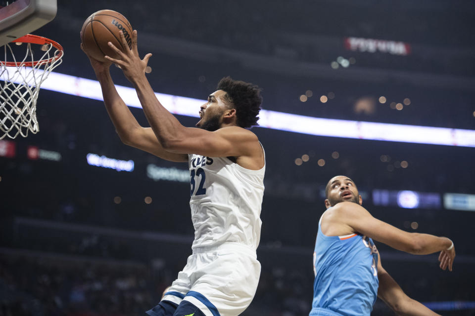 Minnesota Timberwolves center Karl-Anthony Towns (32) goes up for a basket past Los Angeles Clippers forward Nicolas Batum during the first half of an NBA basketball game in Los Angeles Saturday, Nov. 13, 2021. (AP Photo/Kyusung Gong)