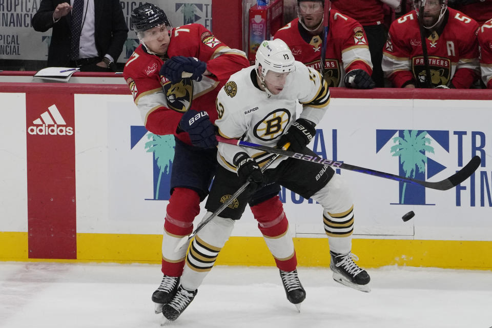 Florida Panthers defenseman Niko Mikkola (77) and Boston Bruins center Charlie Coyle (13) go after the puck during the second period of an NHL hockey game, Wednesday, Nov. 22, 2023, in Sunrise, Fla. (AP Photo/Marta Lavandier)