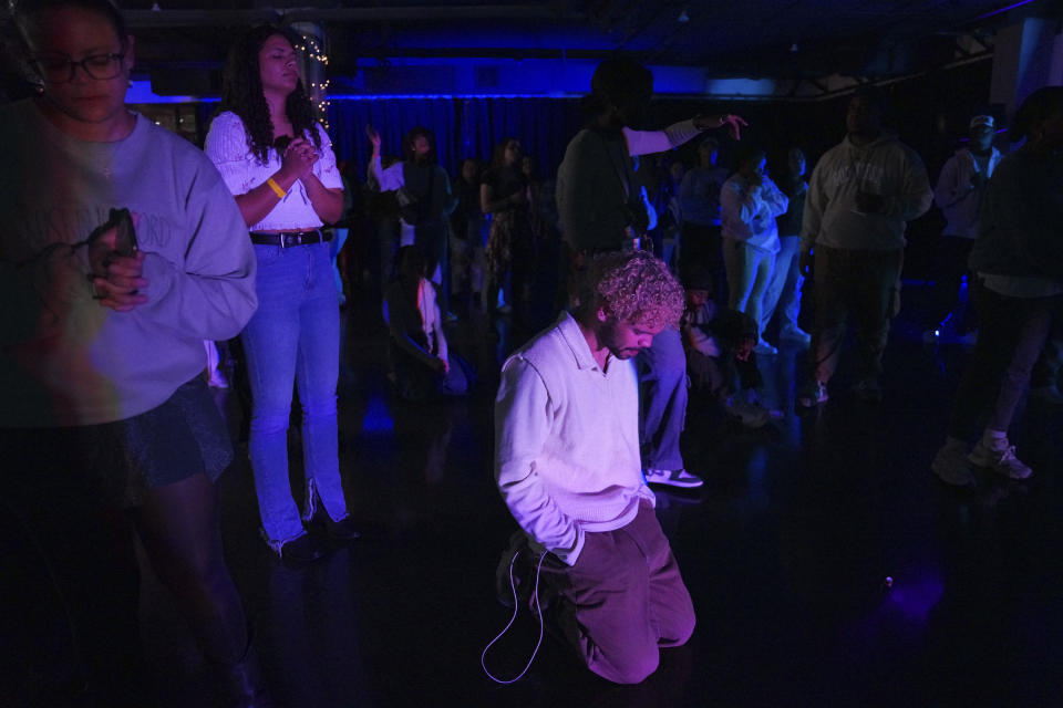 Haynza Posala, 23, center, kneels in prayer during an impromptu worship session at the end of The Cove's third event on Saturday, Feb. 17, 2024, in Nashville, Tenn. The Cove is a pop-up, 18-and-up Christian nightclub started by seven friends in their 20s who sought to build a thriving community and a welcoming space for Christian adults outside houses of worship. (AP Photo/Jessie Wardarski)