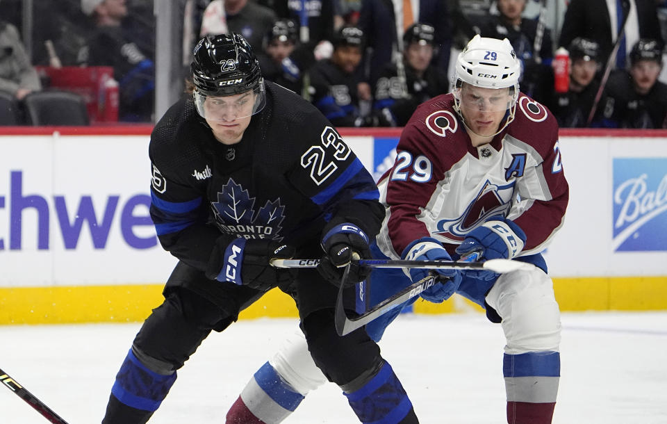 Toronto Maple Leafs left wing Matthew Knies, left, and Colorado Avalanche center Nathan MacKinnon fight for control of the puck in the second period of an NHL hockey game Saturday, Feb. 24, 2024, in Denver. (AP Photo/David Zalubowski)