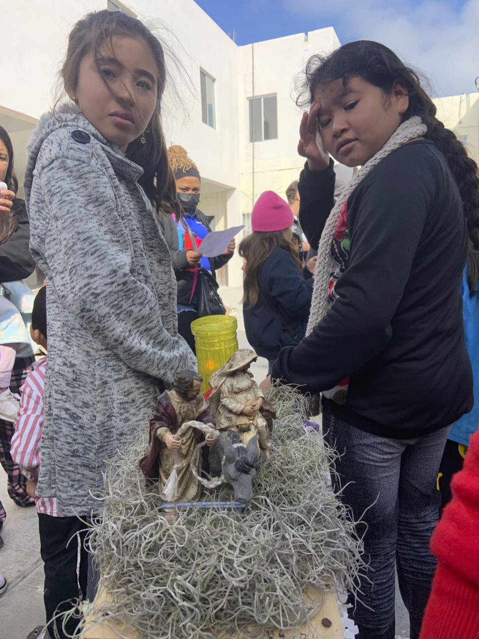 In this photo provided by Father Brian Strassburger, two young girls help to carry the image of Mary and Joseph on the donkey as they journey to Bethlehem, while other migrants sing the traditional songs of La Posada at the Casa del Migrante shelter in Reynosa, Mexico, on Thursday, Dec. 22, 2022. Tens of thousands of migrants who fled violence and poverty will spend Christmas in crowded shelters or on the dangerous streets of Mexican border towns. (Father Brian Strassburger via AP)