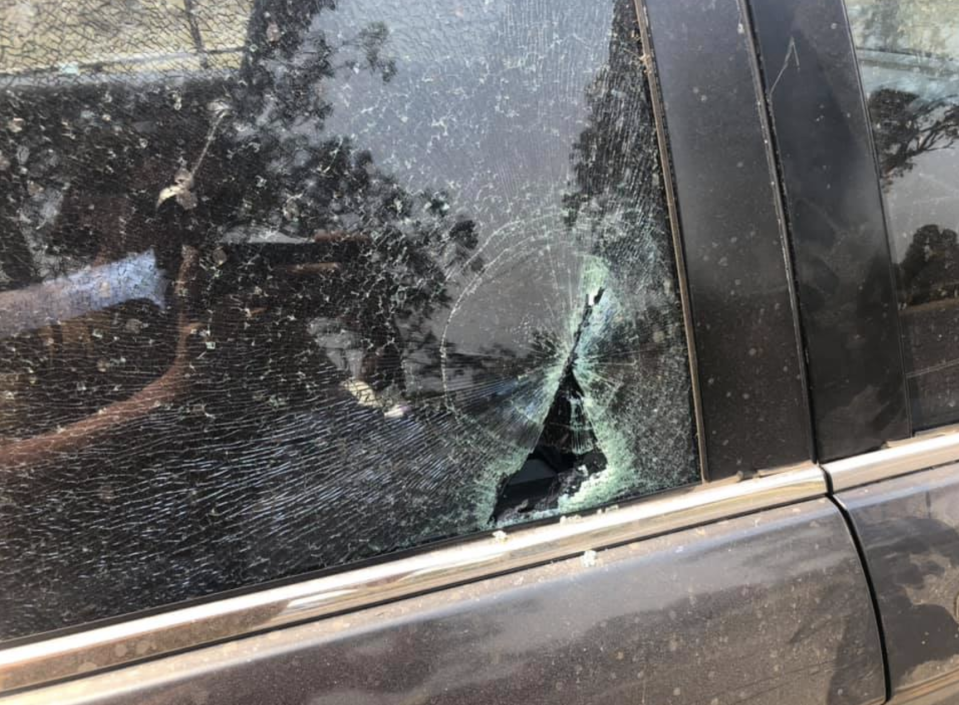 A close up of one of the smashed windows on the man's black car. 