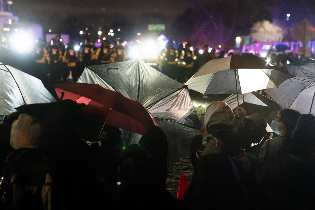 Demonstrators use umbrellas as shields against police during a clash outside the Brooklyn Center Police Department while protesting the shooting death of Daunte Wright, late Tuesday, April 13, 2021, in Brooklyn Center, Minn. (AP Photo/John Minchillo)