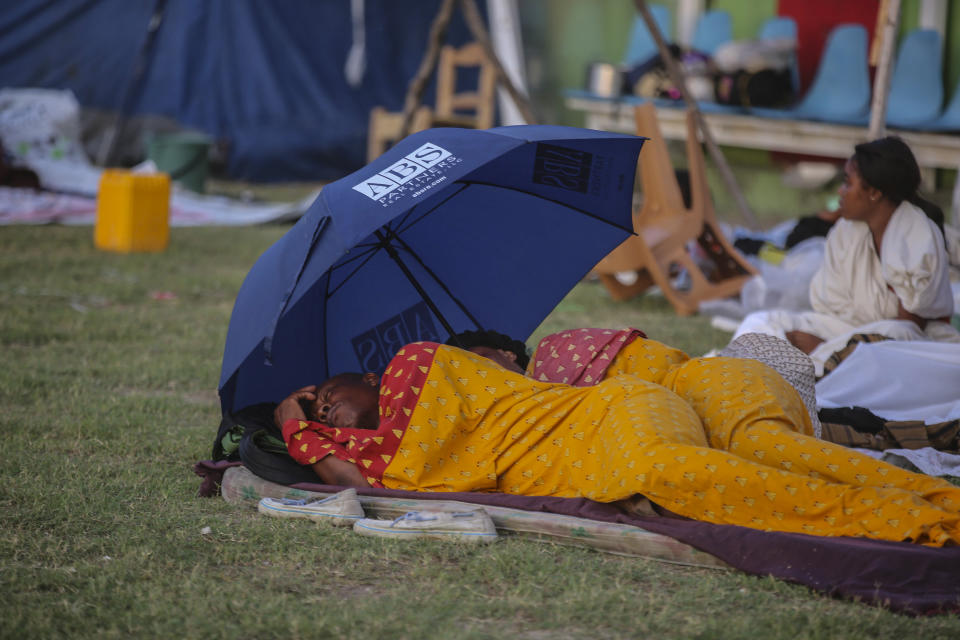 A couple sleeps after spending the night at a soccer field following Saturday´s 7.2 magnitude earthquake in Les Cayes, Haiti, Sunday, Aug. 15, 2021. (AP Photo/Joseph Odelyn)