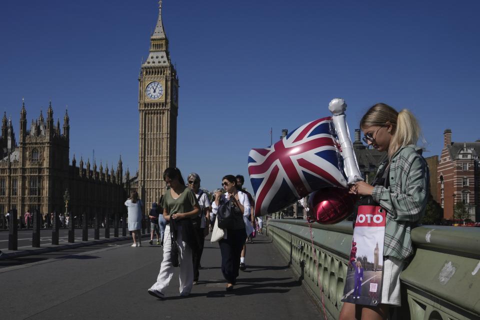 A woman holds a balloon featuring a Union Jack flag near the Houses of Parliament during a sunny day in London, Monday, Sept. 4, 2023. (AP Photo/Kin Cheung)