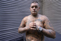 Mike Gilpatrick, who as a teenager was incarcerated at the Youth Development Center, poses showing this tattoos that were inked with a sharpened guitar string while serving time in prison as an adult, at his home, Wednesday, Sept. 8, 2021, in Nashua, N.H. "That place turned us into what we were. I can't say what I am now because I'm a better person now. But coming out of that place, I was a monster.", Gilpatrick said during an interview with the Associated Press. Gilpatrick, 38, filed a lawsuit Monday Sept. 13, alleging he was physically and sexually abused at the former YDC in Manchester, which has been the target of a criminal investigation since 2019 and is slated to close in 2023. (AP Photo/Charles Krupa)