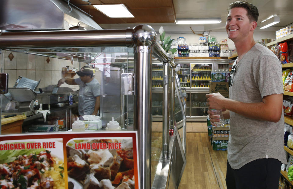 FILE - In this Aug. 25, 2016, file photo, minor league pitcher Gary Cornish banters with employees as he waits for his regular takeout order, iced coffee, a breakfast burrito and a turkey sandwich to go for $13.50 from Mingo's Sandwich Factory, a corner bodega he frequents near the team's hotel in the Brooklyn neighborhood of New York. Major League Baseball is raising the minimum salary for minor league players in 2021, according to a memo sent from the commissioner’s office to all 30 teams obtained by The Associated Press. (AP Photo/Kathy Willens, File)