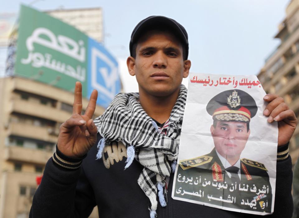 A supporter of Egypt's army chief and defense minister General Abdel Fattah al-Sisi holds a poster with Sisi's image during a protest in support of the new constitution at Tahrir Square in Cairo December 20, 2013. Egyptians will vote on a new constitution on Jan. 14 and 15, pushing on with the army-backed government's plan for transition back to democracy after its overthrow of elected Islamist President Mohamed Mursi. REUTERS/Mohamed Abd El Ghany (EGYPT - Tags: CIVIL UNREST MILITARY POLITICS)