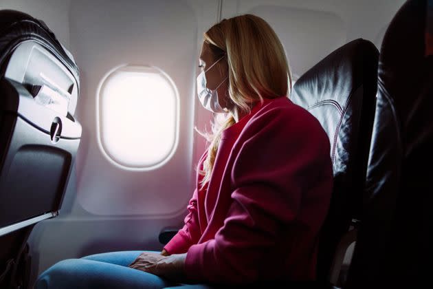 Side shot of a young blond woman sitting in an airplane and looking out of the window (Photo: mihailomilovanovic via Getty Images)