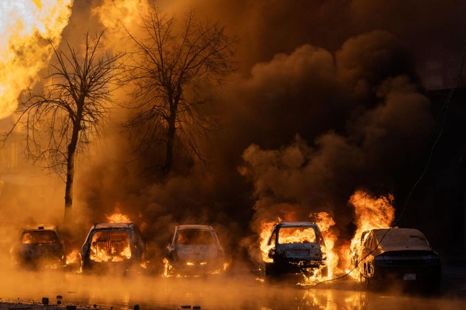 Cars on fire after a Russian attack in Kyiv on Tuesday (AP)