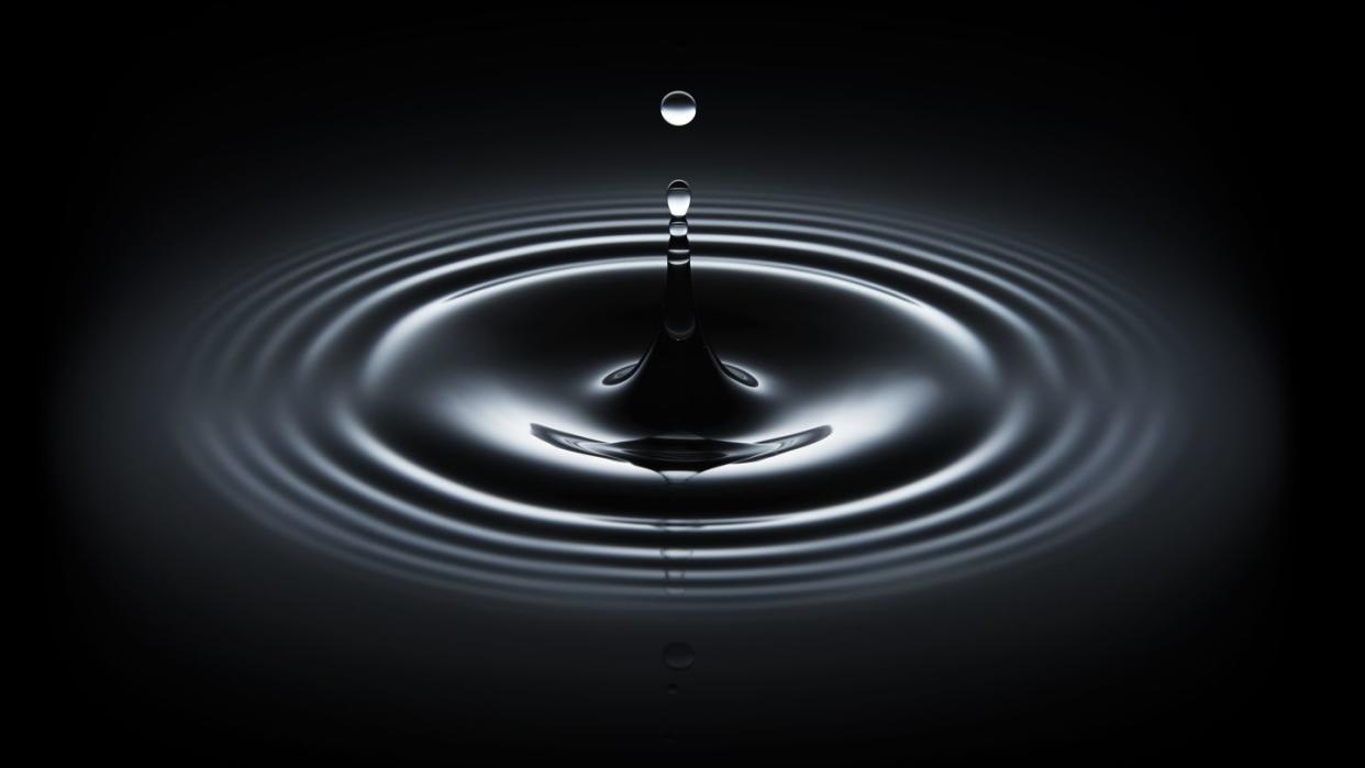 water drop making ripple on black background