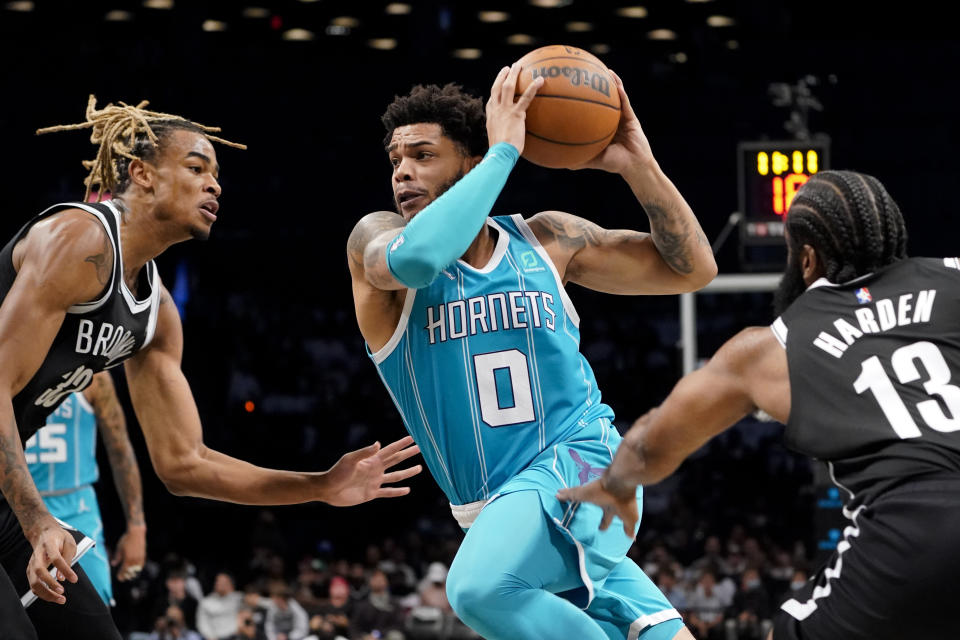 Charlotte Hornets forward Miles Bridges (0) drives past Brooklyn Nets guard James Harden (13) and forward Nic Claxton (33) during the first half of an NBA basketball game, Sunday, Oct. 24, 2021, in New York. (AP Photo/John Minchillo)