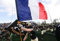 The Army college football team runs onto the field with the French flag.