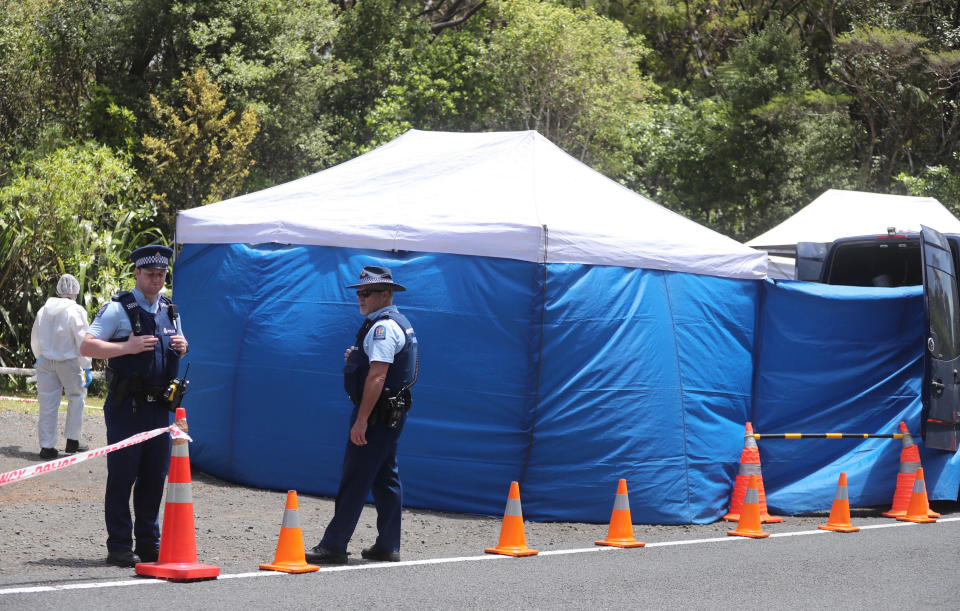 Police investigating the murder of British tourist Grace Millane stand by a cordoned off crime scene along a section of Scenic Drive in the Waitakere Ranges outside Auckland, New Zealand, Sunday, Dec. 9, 2018. New Zealand police said Saturday, Dec. 8, that they believe the 22-year-old British tourist who has been missing for a week was murdered, and they will lay charges against a man they detained earlier in the day for questioning. (Doug Sherring/New Zealand Herald via AP)