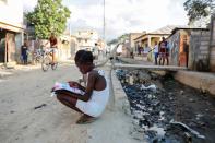 A girl does homework on the street in Port-au-Paix