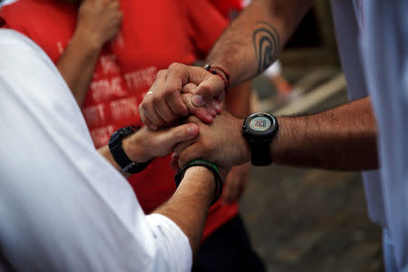 Sergio Colas (R) holds hands with other runners after checking everyone ran safely after the first bull run of the San Fermin festival in Pamplona, northern Spain, July 7, 2016. REUTERS/Susana Vera