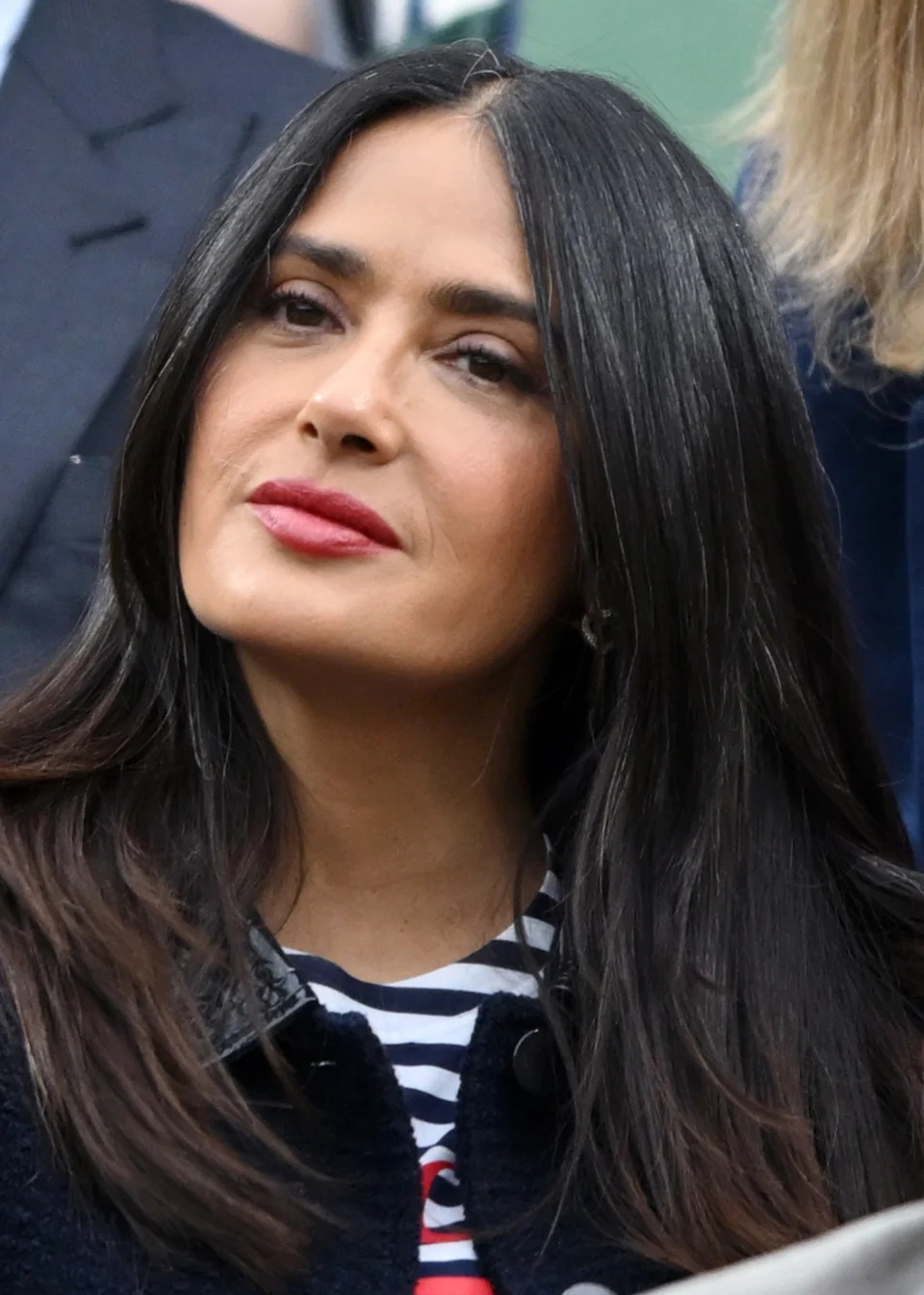 Salma Hayek with long, straight hair and wearing a striped top and a jacket