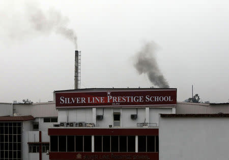 Smoke emitted from factory chimneys is seen behind Silver Line Prestige School in Ghaziabad, on the outskirts of Delhi, India, November 1, 2018. REUTERS/Anushree Fadnavis