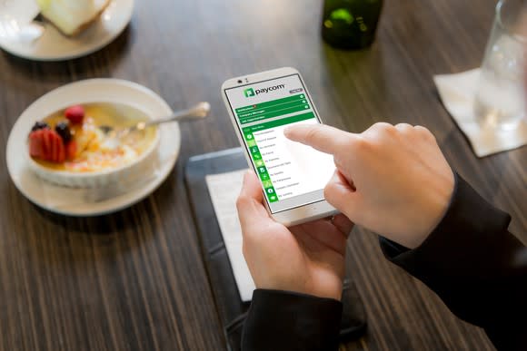 A person using Paycom's expense reporting app on a smartphone