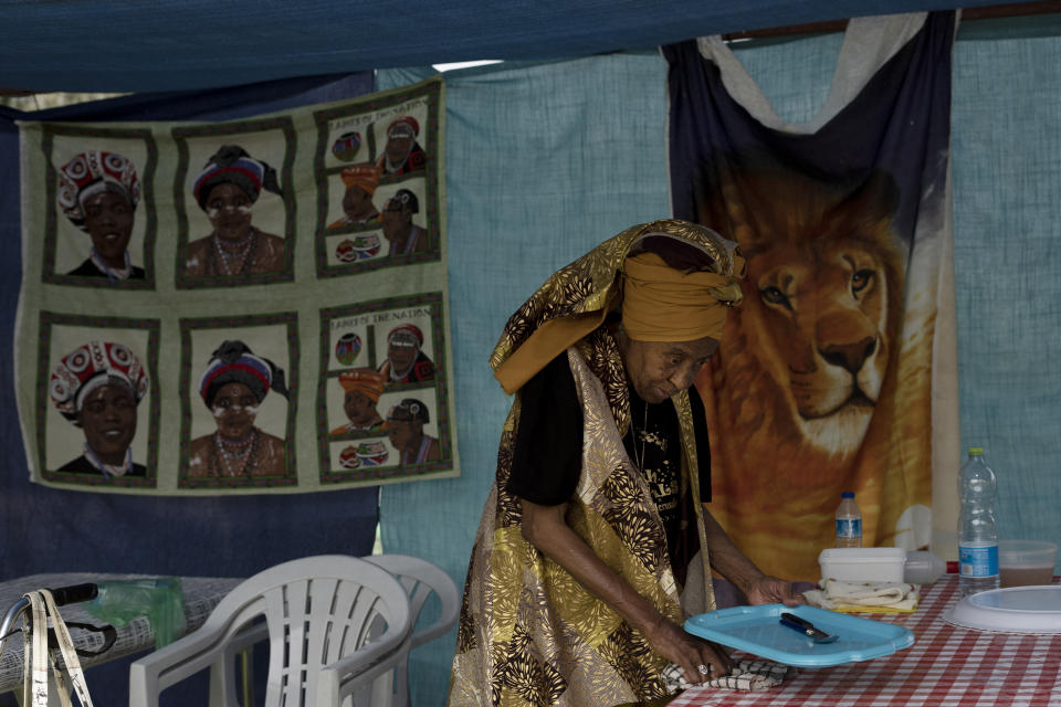 An elderly woman from the African Hebrew Israelites of Jerusalem community tidies her family tent during New World Passover celebrations marking the group's exodus from the United States, in Dimona, Israel, Thursday, June 1, 2023. Shortly after their arrival in Israel, the community's' legal problems began. Israel initially granted them citizenship, but subsequently revoked it after changes in its Law of Return, which grants automatic citizenship to Jews. (AP Photo/Maya Alleruzzo)