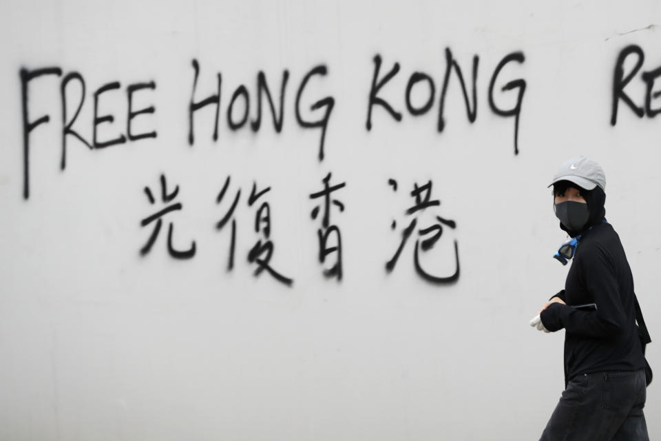 A protester spray-paints a slogan on a wall during a demonstration in Hong Kong, Saturday, Aug. 3, 2019. Hong Kong protesters ignored police warnings and streamed past the designated endpoint for a rally Saturday in the latest of a series of demonstrations targeting the government of the semi-autonomous Chinese territory. (AP Photo/Vincent Thian)