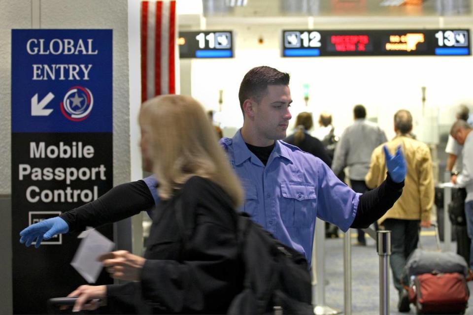 El especialista de operaciones Carlos Martínez guía a los viajeros que arriban al Aeropuerto de Miami hacia los controles de pasaportes que usan aplicaciones de telefonía móvil.