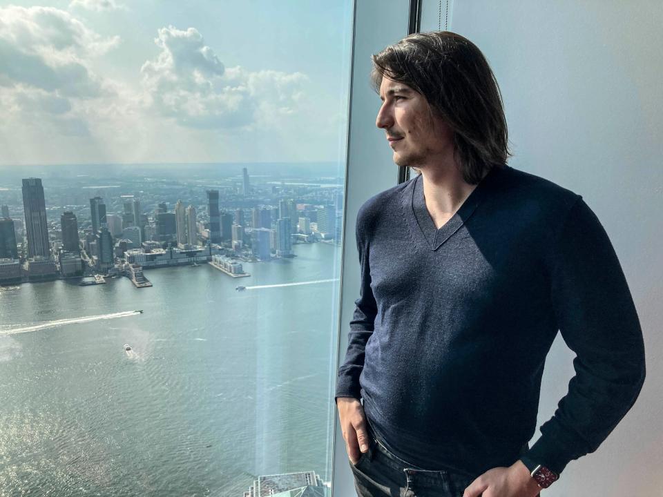 Robinhood CEO Vlad Tenev stands in front of a window overlooking New York City.
