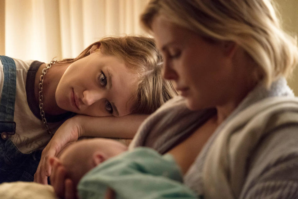 Two women sit and look after a baby