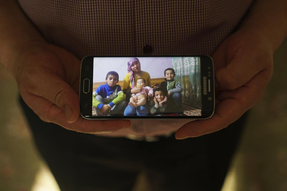 In this Aug. 23, 2018, photo, Adil, 42, father to five children and a businessman from Kashgar, China, holds a phone showing an image of his family left behind in China while being interviewed by the Associated Press in Istanbul, Turkey. He got stuck in Turkey during a business trip after hearing that the Chinese government was seizing passports, and hasn't seen his children since. Three of his children were ordered to attend newly-built boarding schools in Kashgar and Turpan before he got stuck in Turkey. (AP Photo/Dake Kang)