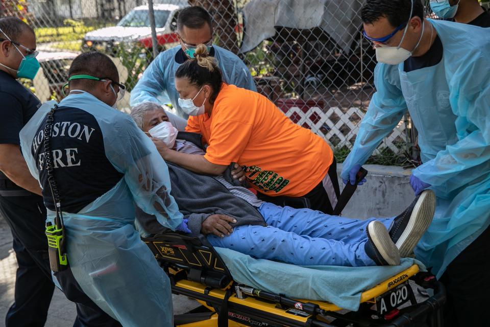 A woman embraces her husband with possible Covid-9 symptoms before medics transported him to a hospital on Aug. 13, 2020, in Houston.