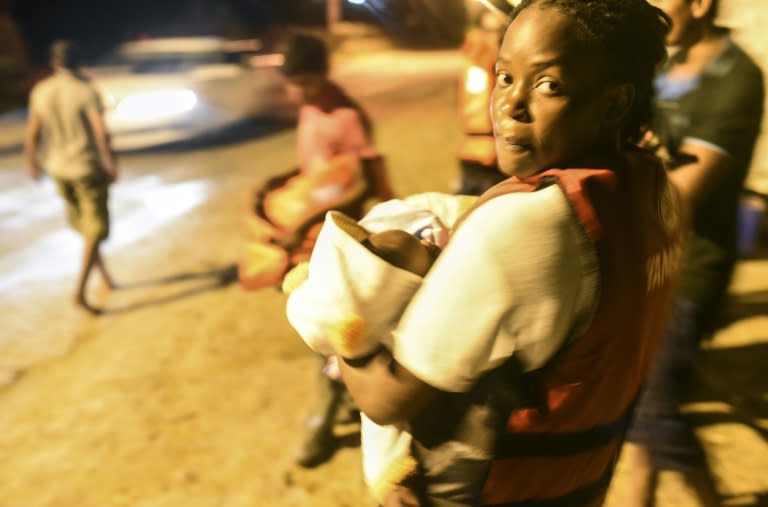 A migrant carrying her baby waits for a boat to reach the Greek island of Kos as Turkish coast guards (not pictured) try to stop them, early on August 20, 2015, near the shore of Bodrum, southwest Turkey