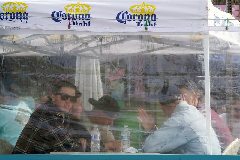People drink and dine outdoors behind a plastic barrier at a bar and restaurant in San Diego