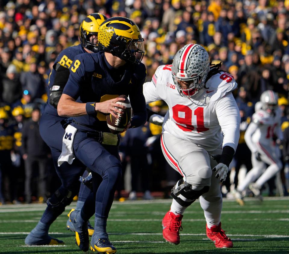 Nov. 25, 2023; Ann Arbor, Mi., USA;
Michigan Wolverines quarterback J.J. McCarthy (9) is pursued by Ohio State Buckeyes defensive tackle Tyleik Williams (91) during the first half of Saturday's NCAA Division I football game at Michigan Stadium.