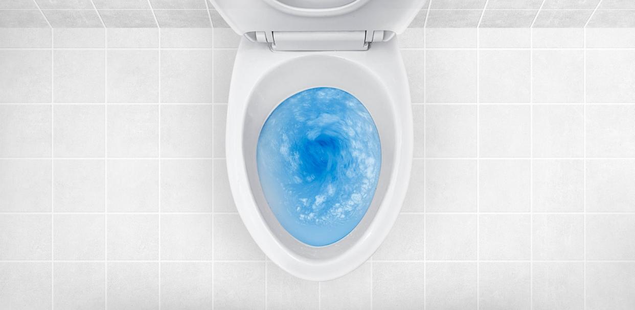 Blue dish soap in a white toilet with the seat up.
