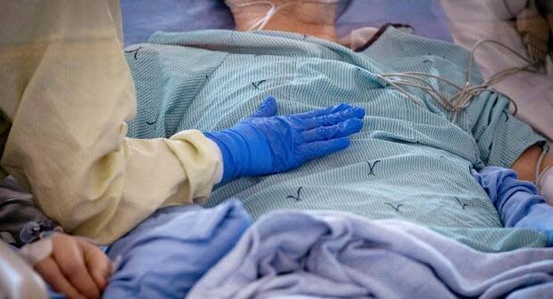 A nurse tends to a patient suspected of having COVID-19 in the ICU of a Toronto hospital in May. Infectious disease specialist Dr. Sumon Chakrabarti says if Canada sees a smaller third wave, or 'wavelet,' the health-care system might be able to 'absorb' the impact of COVID-19 better than previous waves. 