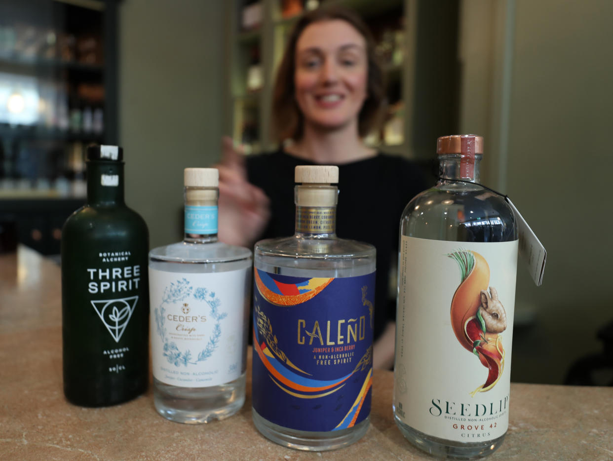 A bartender stands behind four alcohol-free bottles lined up.